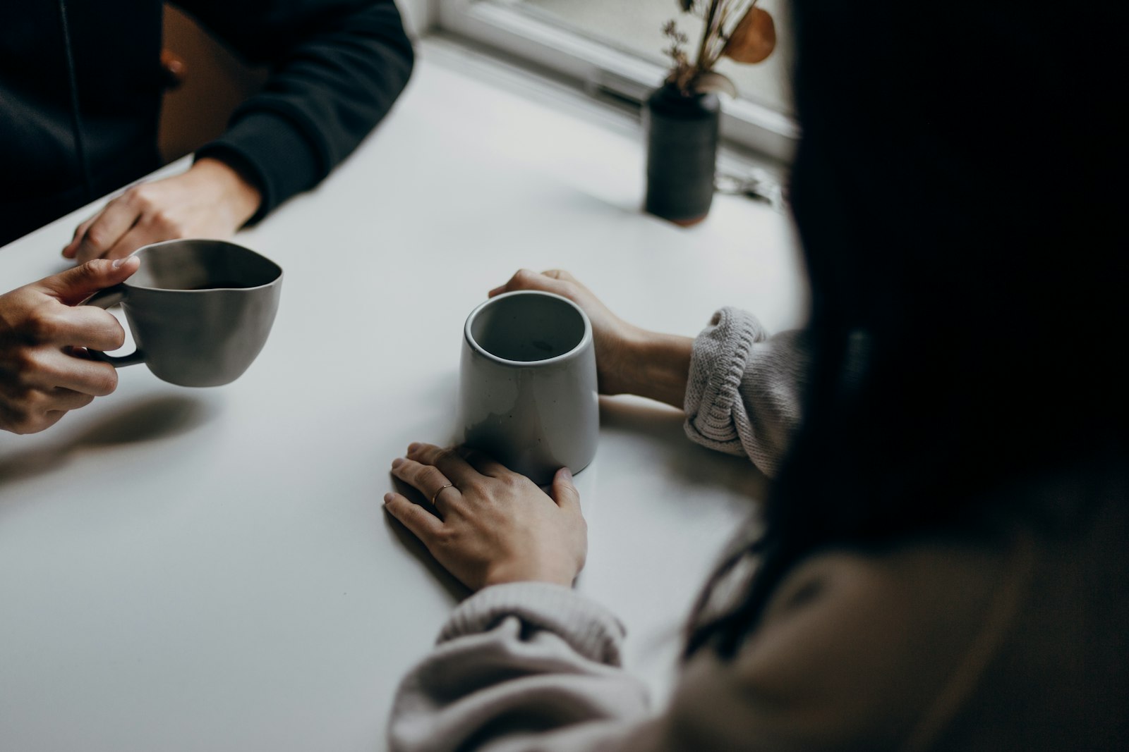 Two people talking quietly over coffee mugs at a table
