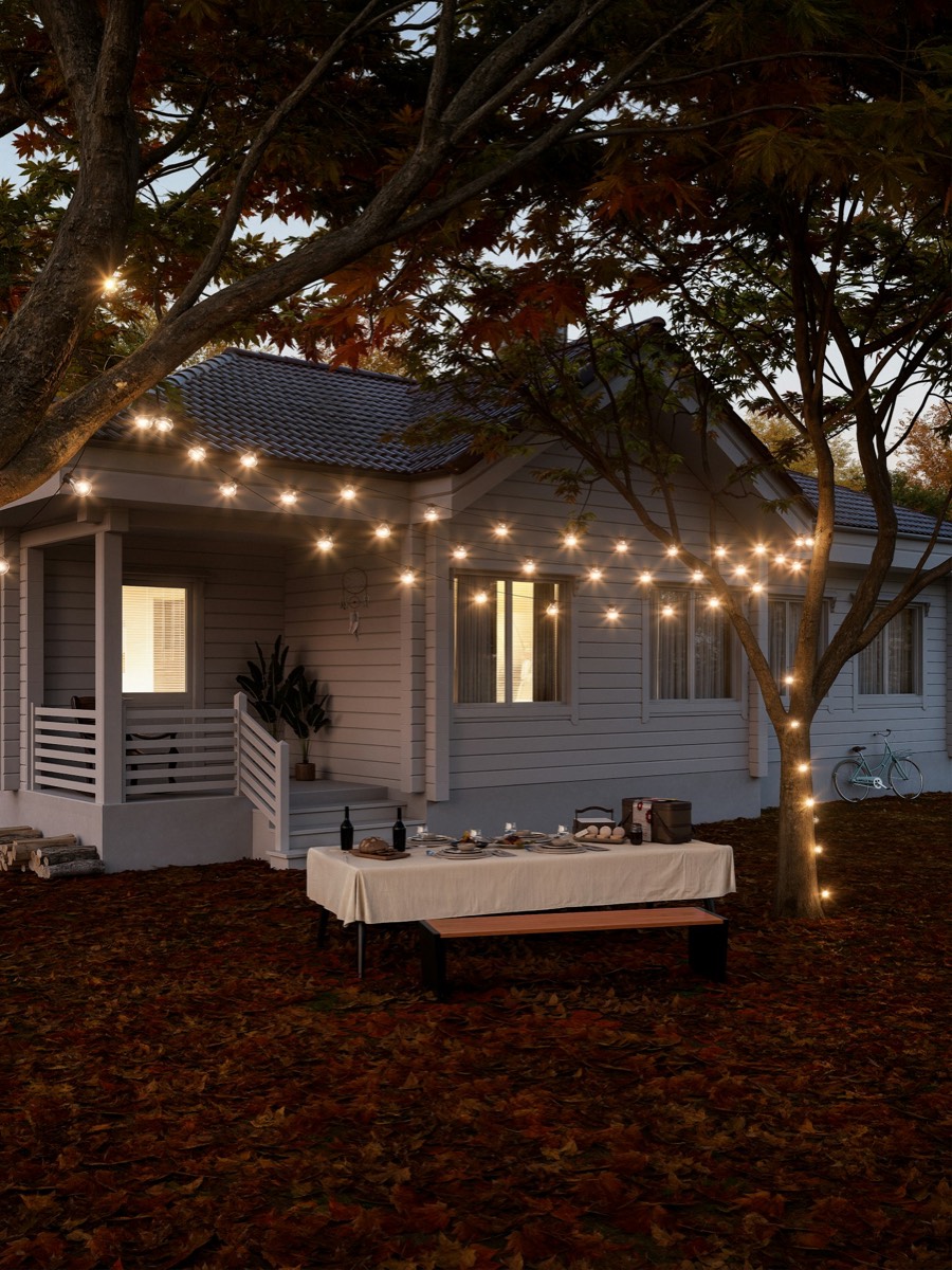 A backyard dinner table set under string lights at dusk