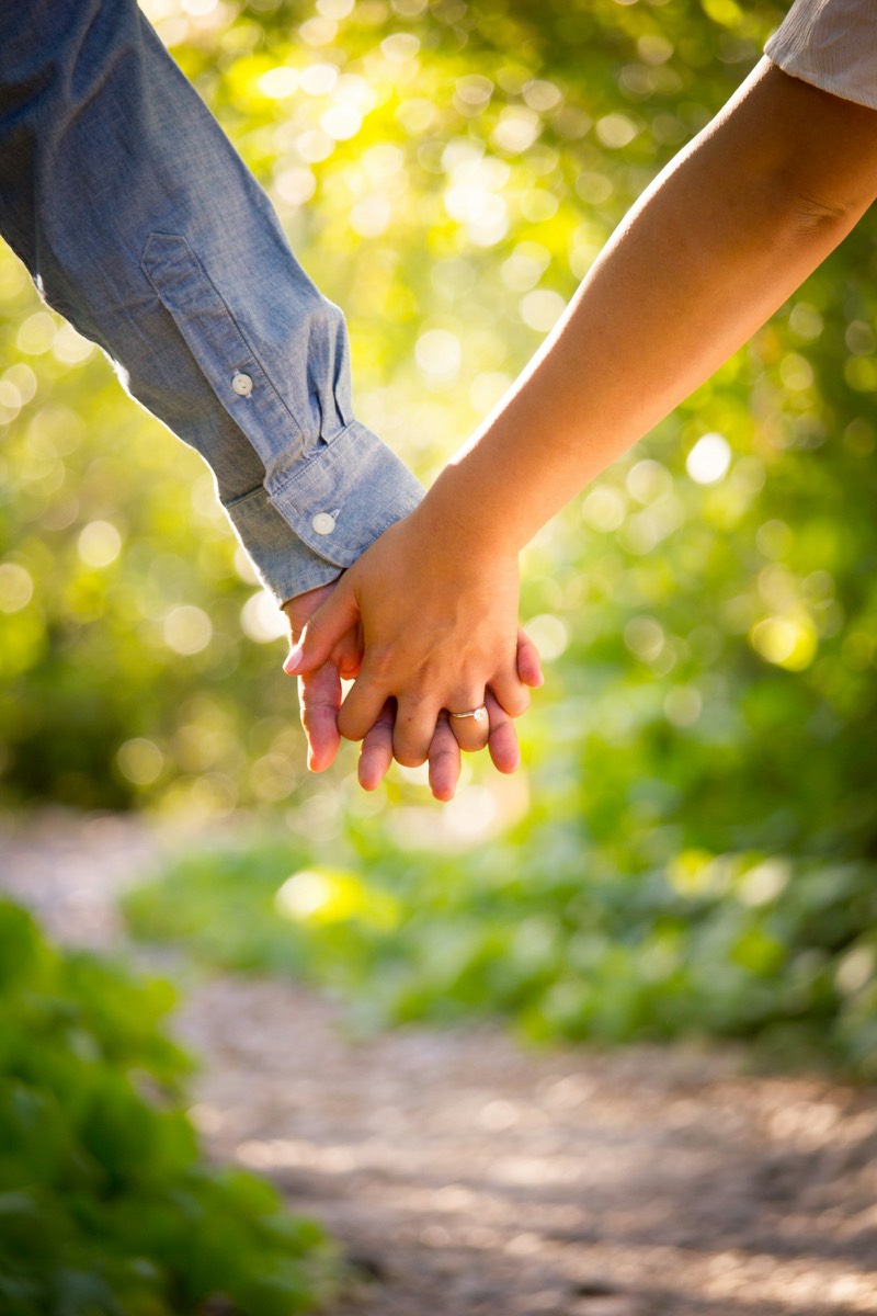 An engaged couple holding hands in warm golden light